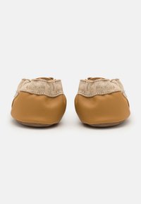 Pantofole in pelle marrone con una parte superiore beige testurizzata, forma arrotondata e suola morbida. Presentano un design arricciato all'apertura della caviglia.