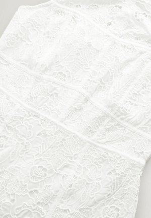 White lace dress featuring intricate floral patterns, textured fabric, and structured panels. The design appears lightweight and delicate.