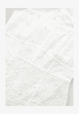 Hvid blondkjole med indviklede blomster mønstre, tekstureret stof og strukturerede paneler. Designet fremstår let og delikat.