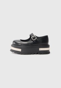 Black leather Mary Jane shoe with silver buckle, thick platform sole, and metallic silver accents on textured rubber outsole.