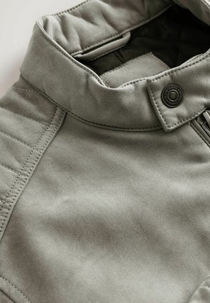 Hall hall nahast kangas lähedalt, millel on voltis krae koos pressnupuga, ühel poolel tikitud muster ja peidetud lukk.