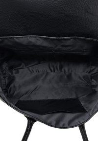 Interiér černé kožené kabelky s hladkým textilním povrchem, kapsou na zip a přihrádkou; minimalistický design bez viditelných kovových akcentů.