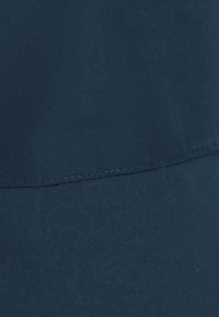 Tissu bleu marine avec une texture lisse, présentant une couture courbée près du haut et une ligne horizontale légèrement plus sombre dans la section inférieure.