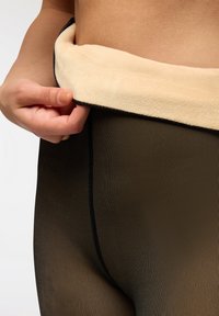 Czarne rajstopy z miękkim beżowym pasem z polaru. Teksturowany materiał charakteryzuje się pionowymi paskami oraz płaskimi szwami na krawędziach.