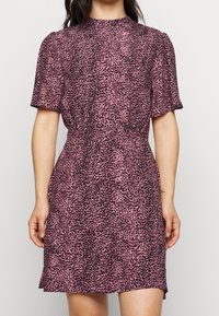 Šaty s krátkým rukávem z rů�žové látky s černým vzorem leopardího tisku, s přiléhavým pasem a rozšířenou sukní pro uvolněnou siluetu.
