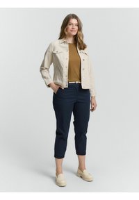 Beige džínová bunda přes hnědý top, spárovaná s námořnickými zkrácenými kalhotami a krémovými nazouvacími botami. Volný střih s knoflíky a ohrnutými manžetami.