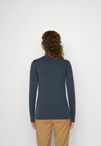 Mörkblå långärmad topp med rund krage, slim fit och mjuk textur, tillsammans med beige byxor. Enkelt mönster, inga synliga mönster eller accenter.