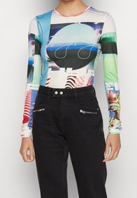 Dlouhý rukáv s multicolor grafickým designem zahrnujícím abstraktní tvary a vzory. Vyroben z elastického materiálu, s přiléhavým střihem.