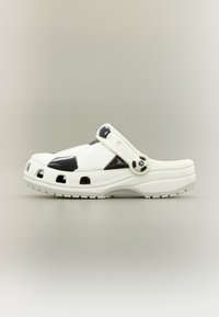 Λευκό παπούτσι τύπου κλογκ με μοτίβο μαύρης ποδοσφαιρικής μπάλας και ρυθμιζόμενο λουρί με μικρή διακόσμηση ποδοσφαιρικής μπάλας.