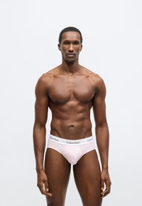 Męskie slipy Calvin Klein w miękkim różowym materiale, z białym elastycznym pasem z logo. Dopasowany fason o gładkiej fakturze.