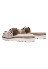 Beige slip-on sandaler med flæset stofremme og tykke hvide teksturerede såler, vist i skrå vinkel på en hvid baggrund.