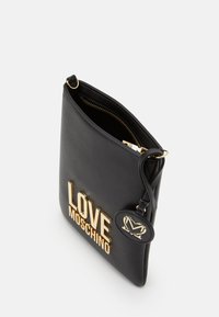 Pochette nera in pelle con logo dorato "LOVE MOSCHINO", zip dorata e etichetta rotonda in pelle nera con emblema dorato attaccata alla tracolla.