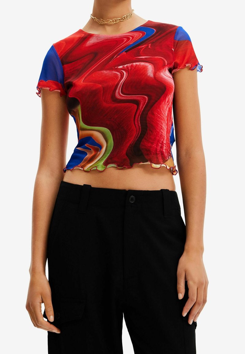 Lyhytnhihainen punainen crop-top, jossa on pyörivä abstrakti kuosisininen, vihreä ja keltainen korostus; röyhelöhelma.