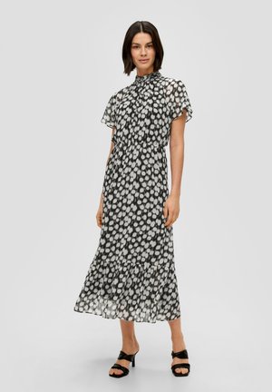 Schwarzes und weißes Pünktchenkleid mit hohem Kragen, kurzen, fließenden Ärmeln und einem plissierten Rock. Mit tailliertem Bund und geschichtetem Saum.