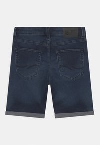 Pantaloni corti in denim blu scuro con orlo arrotolato, dotati di due tasche posteriori e un'etichetta in pelle in vita. Texture liscia, design classico.