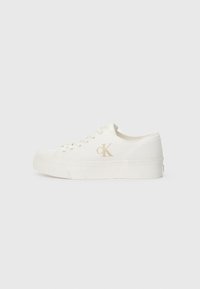 White canvas sneaker with a textured surface, featuring a thick sole, lace-up design, and a subtle gold "CK" logo on the side.
