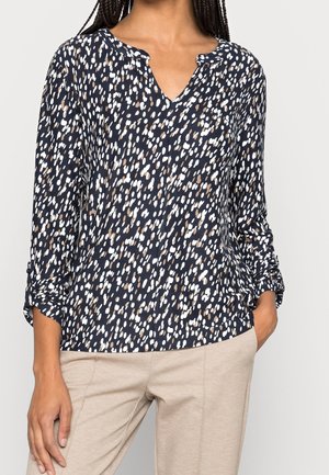 Navybluse mit einem weiß-braun gesprenkelten Muster. Sie verfügt über einen V-Ausschnitt, lange Ärmel mit umgeschlagenen Manschetten und einen weichen, strukturierten Stoff.