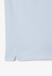 Polo shirt azzurro chiaro realizzato in tessuto testurizzato, caratterizzato da un orlo dritto e spacco laterale per facilitare i movimenti.