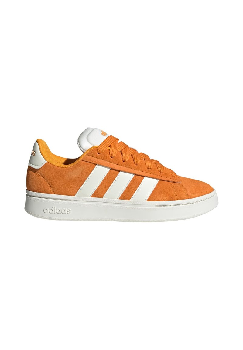 Zapatilla Adidas de ante naranja con rayas blancas, suela blanca y cordones, vista desde el lado externo sobre un fondo blanco.
