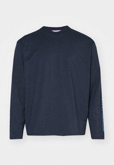 Marineblå långärmad t-shirt av bomull. Har en rundad halsringning och textgrafik i ljusblått på vänster ärm. Slät textur.