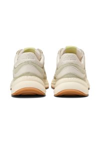 Sneakers grigi e crema con un design texturizzato, caratterizzati da un accento verde sul tallone e una suola in gomma con un motivo di battistrada marrone.