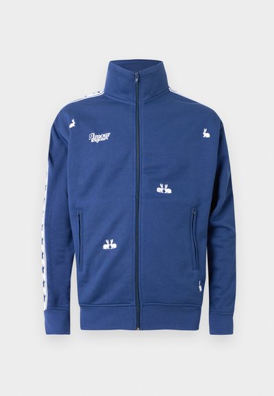 Modrá bunda na zips s bielymi vyšívanými zajacmi, textom "Amour toujours" na hrudi a hviezdičkovým vzorom na rukávoch.