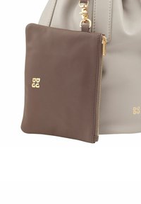 Pochette in pelle marrone con zip attaccata a una borsa a tracolla grigia chiara, caratterizzata da accessori dorati e design con logo in rilievo. Texture liscia complessiva.