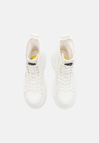 Sneaker alte bianche con una texture liscia, punta tonda e suola spessa. Presentano un design con lacci e un'etichetta con il marchio sulla linguetta.