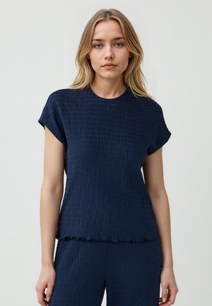 Top blu navy a maniche corte realizzato in tessuto testurizzato con un motivo ondulato e orlo scallop, dotato di scollatura a girocollo.