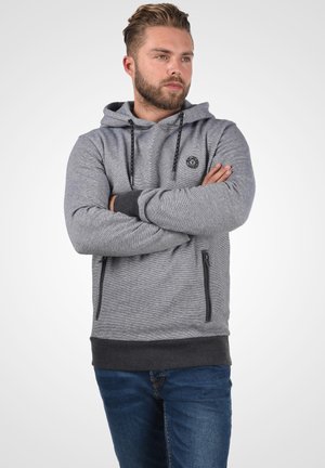 Sudadera gris con tejido texturizado, cordón ajustable, cremalleras negras en los bolsillos y puños y dobladillo gris oscuro. Logo en el pecho.