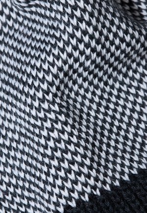 Strickstoff mit einem schwarz-weißen Zickzack-Muster, das sichtbare Textur und Fasern aufweist und ein weiches, gewebtes Design zeigt.