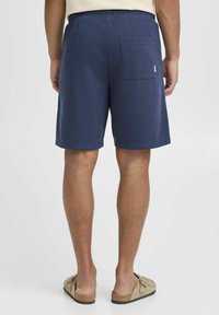 Shorts bleu marine en tissu doux, dotés d'une taille élastique, d'une poche passepoilée à l'arrière et d'une coupe décontractée.
