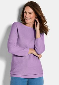 Lila Pullover mit weitem Ausschnitt, gerippten Bündchen und Saum, strukturiertem Stoff, lockerer Passform, kombiniert mit blauen Jeans.