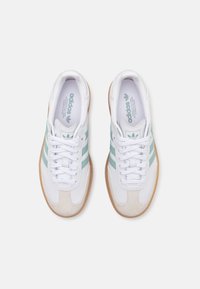 Sneaker bianchi con strisce verde menta, dettagli in suede e suola in gomma. Presentano una chiusura con lacci e un collo imbottito.