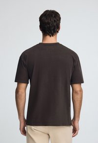 Brun bomull t-shirt, korta ärmar, avslappnad passform, rund halssning, enkel design, ribbad krage, inga synliga mönster eller accenter.