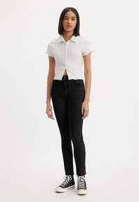 Witte textuur short-sleeve shirt met een kraag, sluiting met knopen, gecombineerd met hoge zwarte skinny jeans en zwarte sneakers.