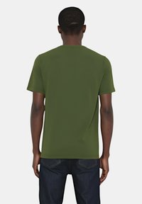 T-shirt verde oliva a maniche corte con scollatura a girocollo, design semplice, texture liscia e vestibilità comoda, abbinato a jeans in denim scuro.