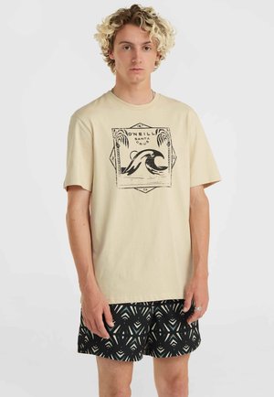 Beige katoenen t-shirt met een zwart golfgrafiek ontwerp. Gecombineerd met zwart met patroon shorts die geometrische vormen in wit en teal tonen.
