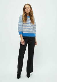 Sinine ja beež triibuline kudumissärk ümmarguse kaelusega ning tekstuursete varrukatega, sobitatud mustade sirgete pükstega ja teravapealsete mustade kingadega.