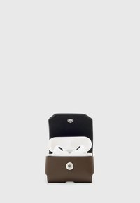 Custodia in pelle marrone con coperchio nero, contiene auricolari wireless bianchi. Presenta un pulsante argento e bordi arrotondati per un design compatto.