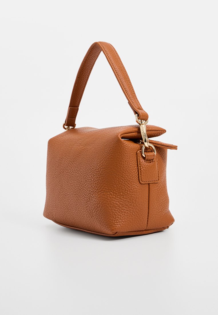 Sac à main en cuir tan avec une surface texturée, de forme rectangulaire compacte, une petite poignée et un petit détail zippé sur le dessus. Accents en métal doré.