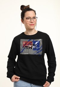 Felpa nera con stampa grafica di un'auto con accenti rossi e blu, su uno sfondo grigio. Tessuto morbido, design a collo rotondo.