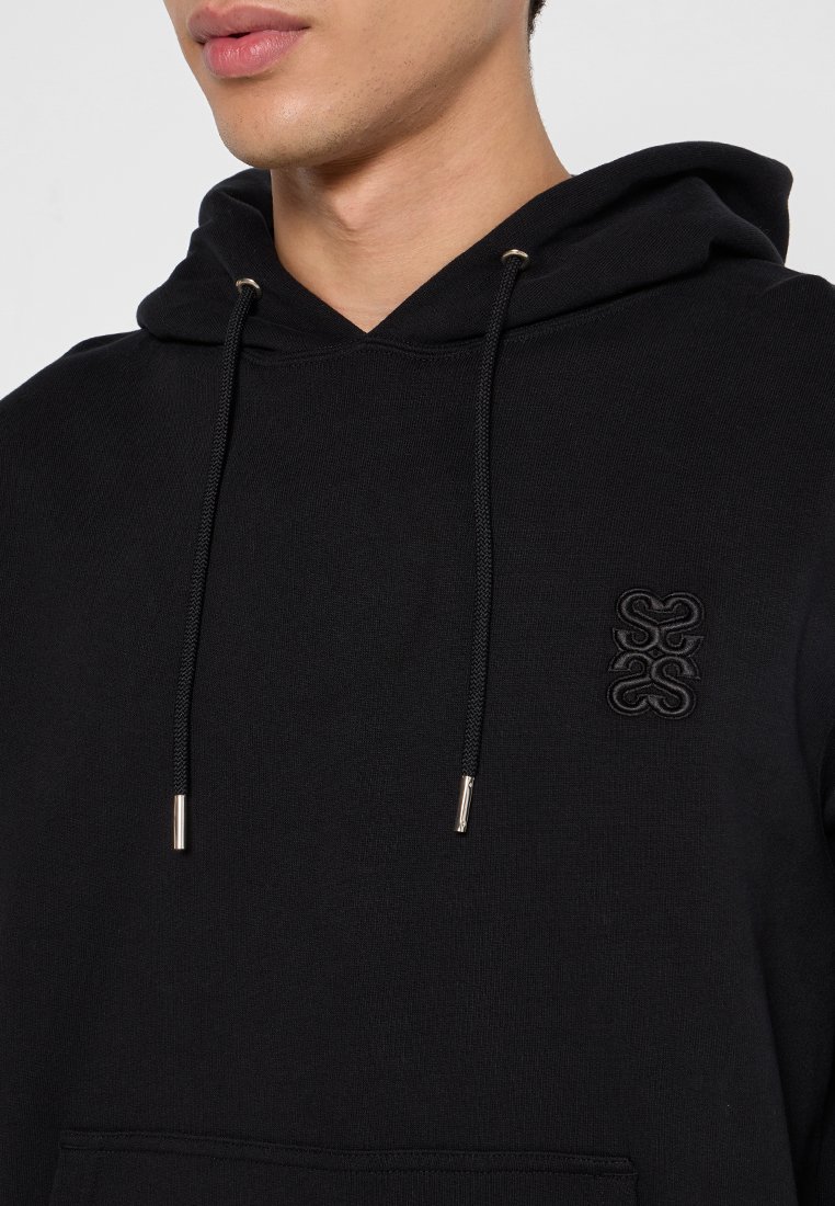 Schwarzer Hoodie aus weichem Material, mit einer vorderen Kängurutasche, einem Kapuzenschnürzug mit Metallenden und einem eingeprägten Logo auf der Brust.