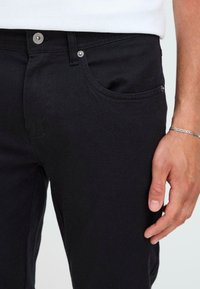 Sorte denim jeans med slim fit, med en frontlomme, sølv knappelukking og synlig søm. Glatt tekstur og ren design.