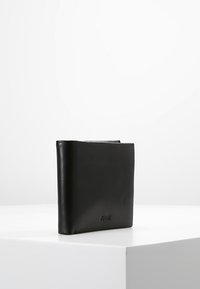 Černá kožená peněženka s hladkým povrchem, čtvercovým tvarem a jemným logem. Minimalistický design bez viditelného hardwaru nebo ozdob.