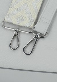 Borsa a tracolla grigia con texture e hardware argentato, dotata di una tracolla crema a motivo e doppi ganci in metallo per la regolazione o rimozione.
