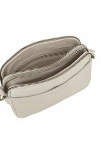 Borsa a tracolla in pelle color beige chiaro con numerosi scomparti con zip, texture liscia, design minimalista e branding sottile sul lato.