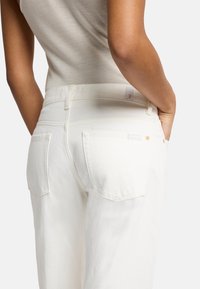Witte denim jeans met een rechte pijp, voorzien van twee achterzakken en een gestikt tailleband. Gladde textuur, minimale hardwaredetails.