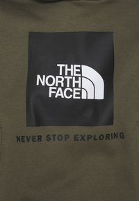 Olivgrön sweatshirt med en svart ruta som har en vit logotyp av "The North Face" och frasen "NEVER STOP EXPLORING" nedanför.