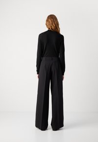 Svarte, høyt belte, vide bukser laget av glatt stoff, med en ren skreddersydd design. Baksiden viser en enkel livlinje.
